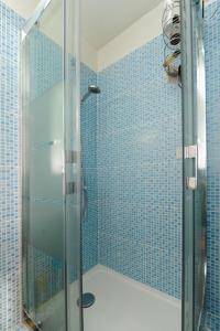 y baño con ducha de azulejos azules. en Blue Lagon Five Stars Holiday House, en Niza