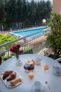 - une table avec des pâtisseries et une vue sur la piscine dans l'établissement Residence Pian Dei Boschi, à Pietra Ligure