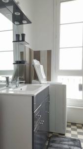 uma cozinha com um balcão branco e um lavatório em Spacieux 2 pièces dans l'hyper-centre em Royan