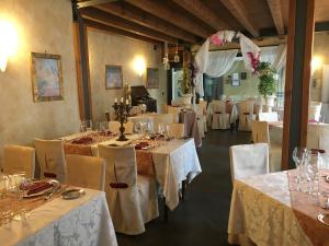 hotel alla busa في Noventa Vicentina: غرفة طعام مع طاولات وكراسي بيضاء