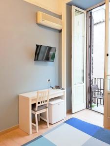 ナポリにあるHotel Meublè Santa Chiara Suiteのデスク、壁掛けテレビが備わる客室です。