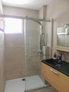 Un baño con ducha de cristal con lavabo. en Mas Les Romarins, en Montesquieu