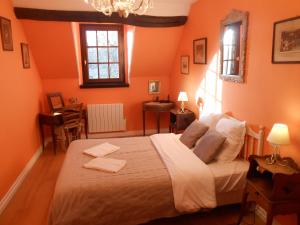 PontlevoyにあるB&B La Ferme des Bordesのオレンジ色の壁のベッドルーム1室(大型ベッド1台付)