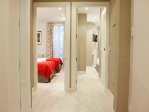 korytarzem prowadzącym do sypialni z czerwonym łóżkiem w obiekcie Feelathome Madrid Suites Apartments w Madrycie