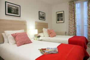 2 camas con almohadas rojas y blancas en una habitación en Feelathome Madrid Suites Apartments, en Madrid
