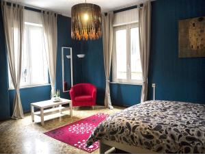 a blue bedroom with a bed and a red chair at B&b Arco Etrusco in Perugia