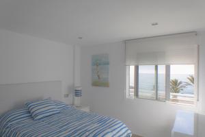 a white bedroom with a bed and a window at Apartamento Mediterráneo in Rincón de la Victoria