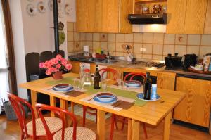 スコペッロにあるValsesia, Monterosa, ampio bilocale, piscina, tennisのキッチン(木製テーブル、赤い椅子、テーブル席付)