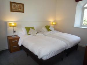 two beds in a room with white sheets and green pillows at Castlemartyr Holiday Mews 2 bed by Trident Holiday Homes in Castlemartyr
