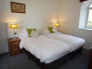 two beds in a room with white sheets and green pillows at Castlemartyr Holiday Mews 2 bed in Castlemartyr