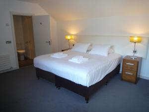 1 dormitorio con 1 cama blanca grande y 2 toallas en Castlemartyr Holiday Mews 3 bed en Castlemartyr