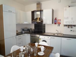 a kitchen with a wooden table and white cabinets at Castlemartyr Holiday Mews 3 bed in Castlemartyr
