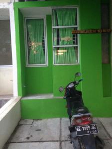 skuter zaparkowany przed zielonym domem w obiekcie Olivine House w mieście Bandar Lampung