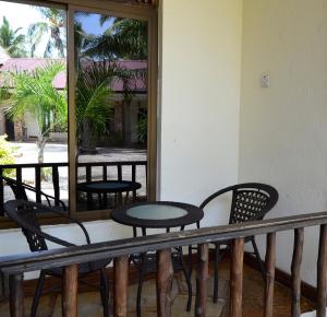 uma varanda com cadeiras, uma mesa e um espelho em Serene Beach Resort em Dar es Salaam