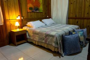 a bedroom with a bed and a table with a lamp at Zululand Bangalôs in Guarda do Embaú
