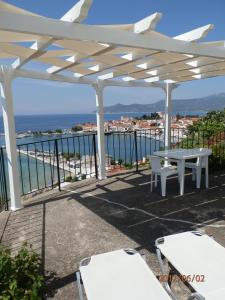 una pérgola blanca con mesa, sillas y el océano en Samos Rooms en Pythagoreio