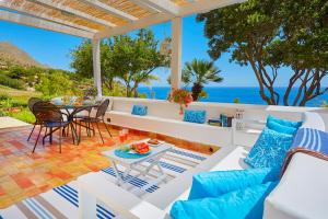 a patio with a table and chairs and the ocean at Villa Ginestra - Scopello-Villas in Scopello