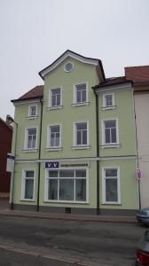 un bâtiment vert avec des fenêtres blanches sur une rue dans l'établissement Pension Haus Maria, à Mühlhausen