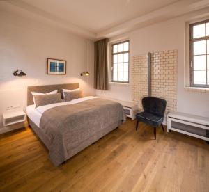 a bedroom with a large bed and a chair at Hotel Oderberger in Berlin