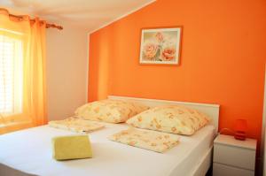 um quarto com paredes cor-de-laranja e uma cama com 2 almofadas em Apartments Mandaric em Trogir