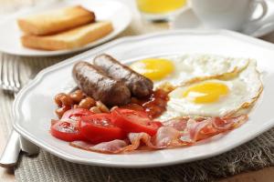 a plate of breakfast food with eggs sausage and tomatoes at Green Bowl Beach Villas in Uluwatu