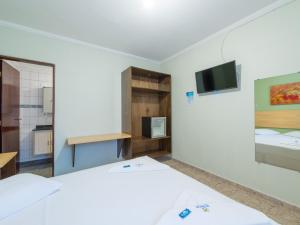 a bedroom with a bed and a tv on a wall at Hotel Venice Ubatuba in Ubatuba
