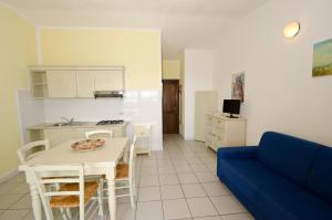 een woonkamer met een blauwe bank en een keuken bij A.I.R. Isola Rossa Borgo di Mare in Isola Rossa