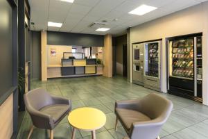 a waiting room with chairs and a table and a drink cooler at B&B HOTEL Toulouse Centre Canal du Midi in Toulouse