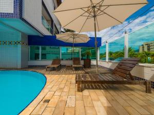a pool with chairs and umbrellas next to a building at Hotel Venice Ubatuba in Ubatuba