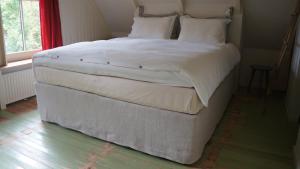 ein großes weißes Bett in einem Zimmer mit Fenster in der Unterkunft Pastorie De Waal in De Waal