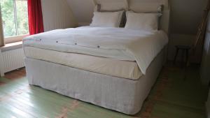 a large white bed in a room with a window at Pastorie De Waal in De Waal