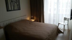 a bedroom with a bed and a window and a chair at Malūno Vilos apartamentai centre in Palanga