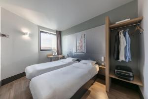 トゥールーズにあるB&B HOTEL Toulouse Centre Canal du Midiのベッド2台とクローゼットが備わるホテルルームです。