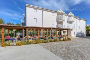 a building with tables and chairs in front of it at Apartments Lola in Rogoznica