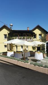 un gruppo di tavoli con ombrelloni di fronte a un edificio di Guest House Grgin Dol a Požega