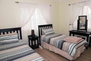 1 dormitorio con 2 camas, espejo y cortinas en Good Times Self Catering Apartments, en Swakopmund