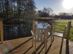 two chairs sitting on a deck next to a pond at Waterside Shepherds Hut in York