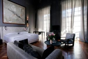 een slaapkamer met een bed, een bank en een tafel bij CoolRooms Palacio Villapanés in Sevilla