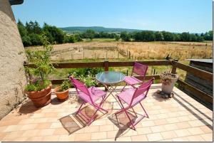 un patio con sillas rosas y una mesa de cristal en Chez Camille, en Étrigny