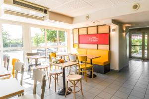 a restaurant with tables and chairs and windows at B&B HOTEL Troyes Barberey in Troyes