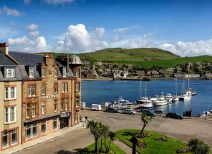 The Royal Hotel Campbeltown في كامبيلتاون: مبنى بجانب مرسى فيه قوارب في الماء