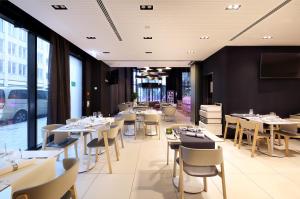 a restaurant with white tables and chairs and windows at Eurostars Book Hotel in Munich