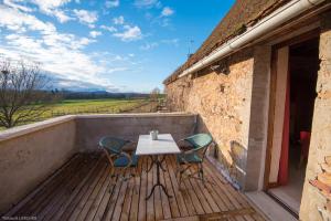 una mesa y sillas en un balcón con vistas a un campo en Ferme de Malo, en Étrigny