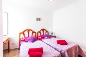 um quarto com 2 camas com almofadas vermelhas e roxas em Vivienda Vacacional Playamar em Playa Honda