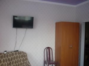 アルヒズにあるГостевой дом У Яшиの壁にテレビと椅子が備わる客室です。