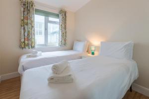 2 weiße Betten in einem Zimmer mit Fenster in der Unterkunft Sole Bay View in Sizewell
