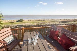 a wooden deck with a table with a bottle of wine at Sole Bay View in Sizewell