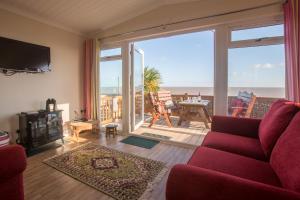 a living room with a red couch and a view of the ocean at Sole Bay View in Sizewell