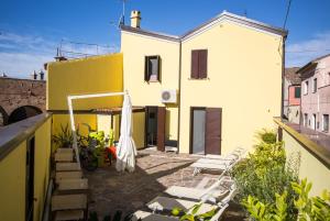 ein gelbes Haus mit einer Terrasse und einem Gebäude in der Unterkunft Dal Marinaio in Comacchio