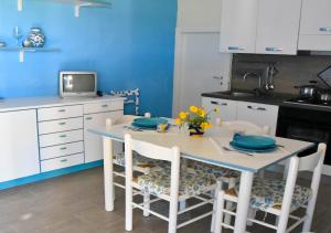 kuchnia z białym stołem z krzesłami i telewizorem w obiekcie Casa Vacanze Portopalo di Capopassero w mieście Portopalo
